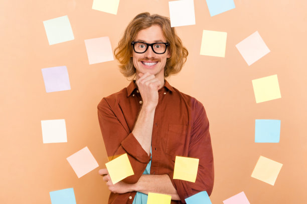 有吸引力的肖像开朗的思想红头发的家伙选择备忘录卡墙解决方案孤立米色粉彩背景图片下载