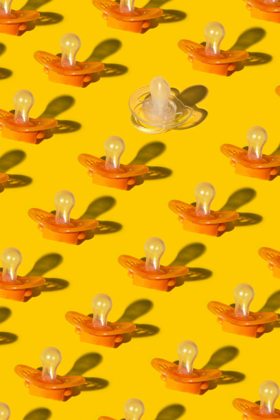 最小的儿童可爱概念。可爱的图案，橙色婴儿奶嘴破碎与白色透明婴儿奶嘴图片下载