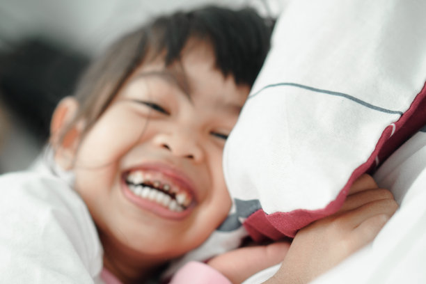 可爱可爱的亚洲小女孩躺在白色的床上的毛毯下。可爱的黑头发白人孩子的特写肖像图片下载