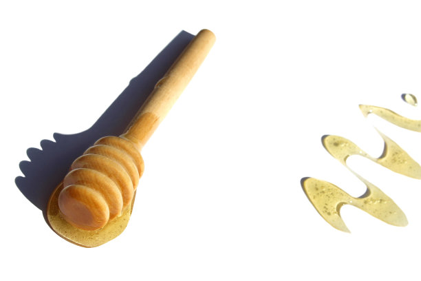 白色背景上洒了蜂蜜的木制勺。图片下载