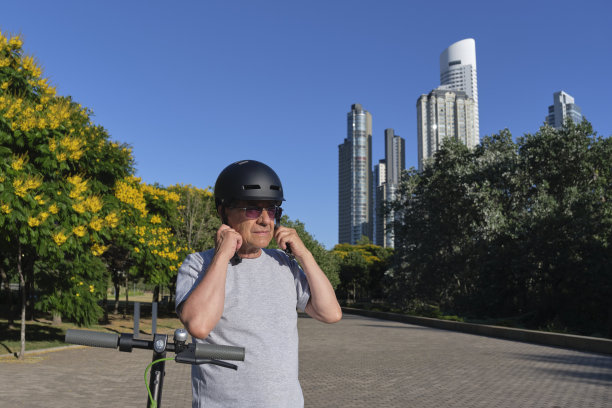 戴头盔骑电动滑板车的拉丁裔老年男人图片下载