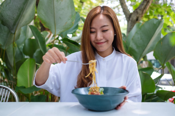一名年轻女子在户外餐厅吃意大利面的肖像图像图片下载