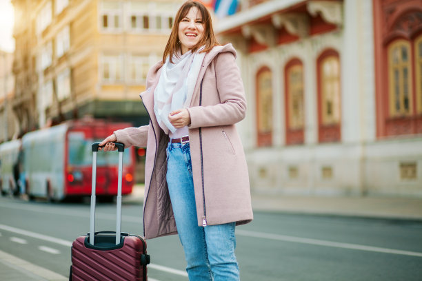 年轻的女游客走手提箱和看向别处图片下载