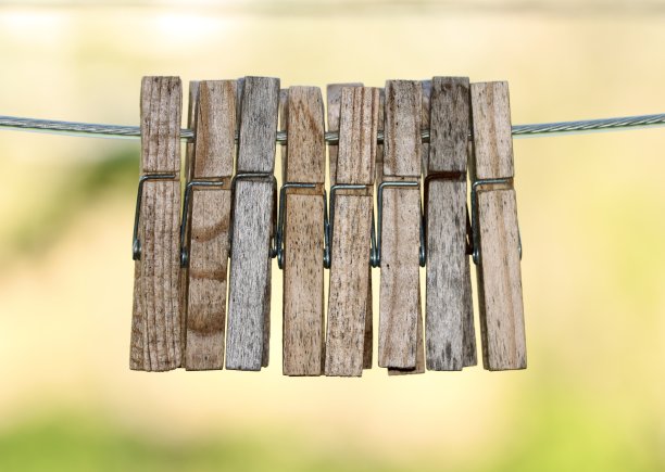 木制衣夹挂在钢晾衣绳上。漂亮的焦外成像。绿色和黄色背景。抽象的艺术图片下载