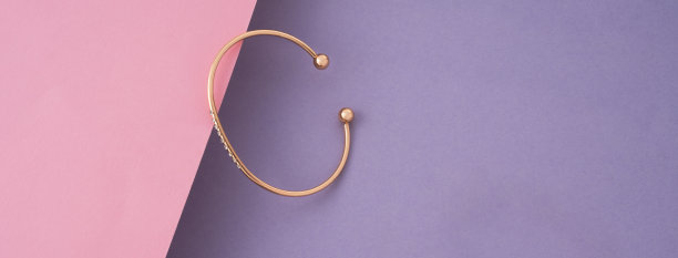 全景的现代金色手镯在粉红色和紫色的纸上拷贝空间图片下载