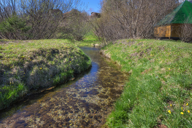 春景有天然的泉水，在阳光明媚的日子里流水潺潺。丘陵地形，蓝天碧水图片下载
