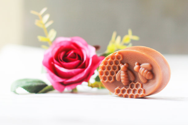 玫瑰手工香皂与盛开的玫瑰在白色木地板上合影。,草药肥皂。,特写照片。图片下载