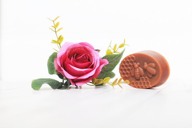 玫瑰手工香皂与盛开的玫瑰在白色木地板上合影。,草药肥皂。,特写照片。图片下载