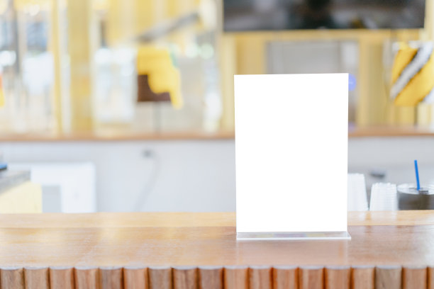 模拟标签的空白菜单框在酒吧餐厅，站小册子与白纸亚克力帐篷卡在木桌自助餐厅模糊的背景可以插入客户的文字。图片下载