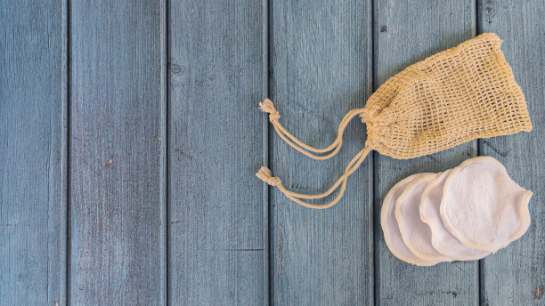 天然棉可重复使用卸妆垫在生态袋蓝色木制背景。平铺，拷贝空间。无塑料，零浪费。有机护肤用品图片下载