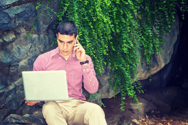 在纽约，一个年轻人在户外用笔记本电脑工作，打电话图片下载