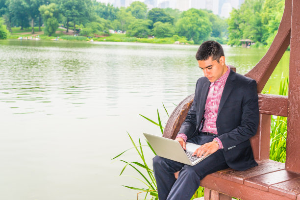 纽约湖边，一个年轻人在户外用笔记本电脑工作图片下载