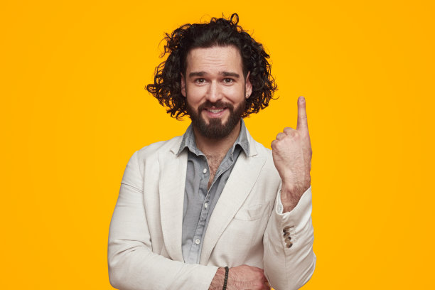 在黄色的画室里，一个满脸笑容、没刮胡子的年轻人指着上面图片下载