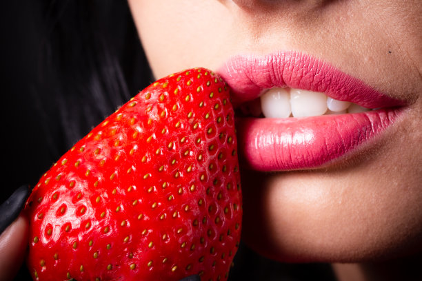 褐发美女的肖像，草莓上滴着蜂蜜。图片下载