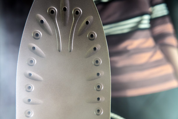 一个家庭主妇手里拿着一个热气腾腾的熨斗。洗衣女工正在烫衣服。现代生活方式的概念，一个在家熨衣服的女人图片下载