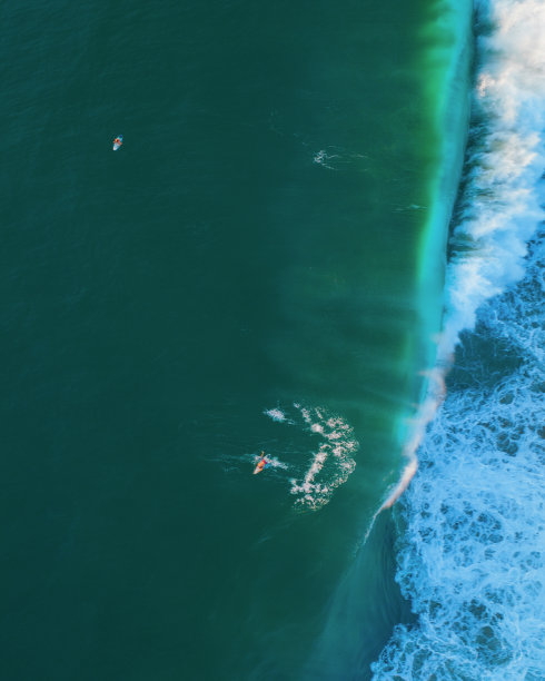 日落时分在埃斯孔迪多港海滩冲浪的鸟瞰图图片下载