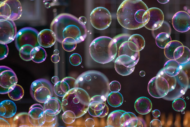 巨大的肥皂泡在阳光下闪闪发光，五彩缤纷的孩子们在脆弱的轻盈中玩耍，巨大的巨大的肥皂泡在风中传播着快乐和幸福，在阳光下闪闪发光图片下载