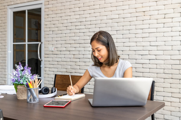 亚洲女性自由职业者的肖像在家里工作，坐在书桌餐桌在客厅图片下载