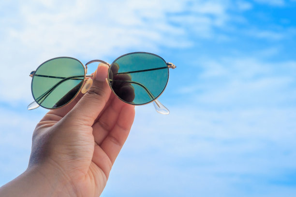夏日旅行理念，一名女子手拿墨镜向天空挥手。图片下载