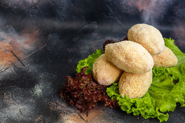 半成品肉片，涂有面包屑的奶酪或黄油。快餐食品准备。在黑暗的背景上。图片下载