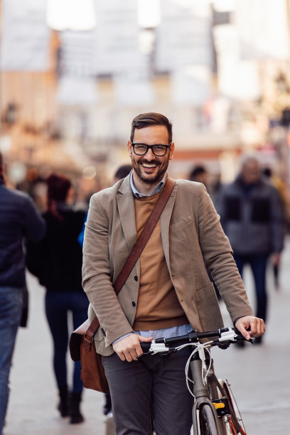 优雅的白人男子的肖像，推着他的自行车穿过拥挤的街道。图片下载