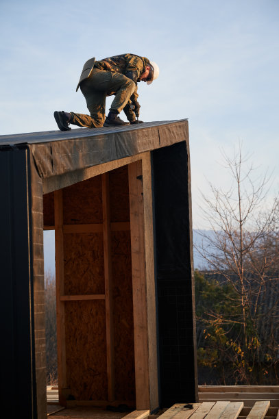 建筑师正在安装波纹铁板作为未来木结构房屋的立面。图片下载