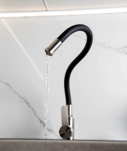 现代厨房水龙头与弯曲的壶嘴设置在白色陶瓷瓷砖。带有黑色弯曲软管的水龙头，特写图片下载