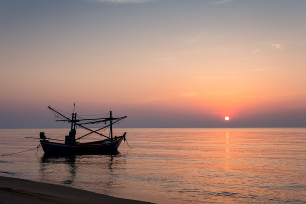 日出的沙滩上渔船图片下载
