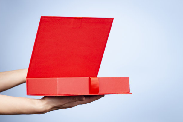 女性双手打开红色典雅的豪华彩带盒。在浅蓝色的背景上模拟礼物盒。前视图图片下载