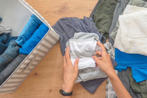 垂直存放衣物，近藤麻理惠整理方法，房间清洁概念。女人用手整理和分类篮子里的衣服。俯视图图片下载