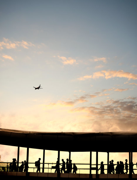 剪影的人和飞行的商业飞机在机场在夕阳的天空图片下载