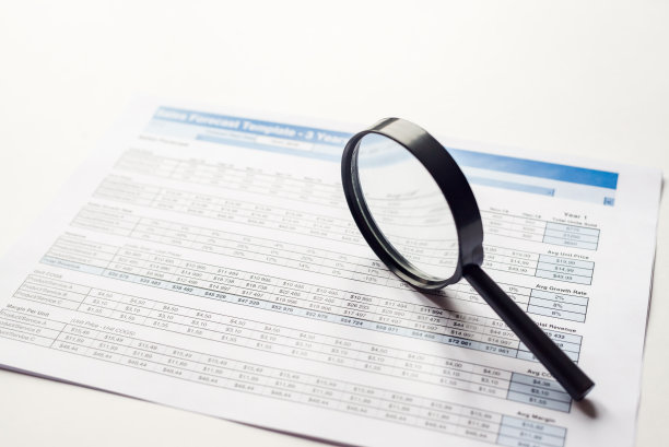 经营理念。放大镜在纸的背景与财务数据图片下载