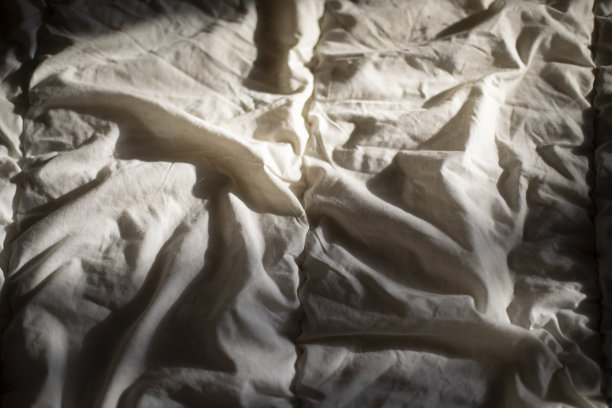 在床上垫床单。织物在阳光下的纹理。图片下载