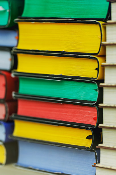 在书店的玻璃橱窗里，许多五颜六色的书堆叠在一起。图片下载