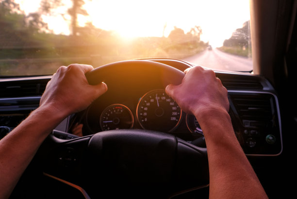 一位女士开车在路上，她正在智能手机上寻找GPS地图，以便到达目的地。技术与道路交通的概念图片下载