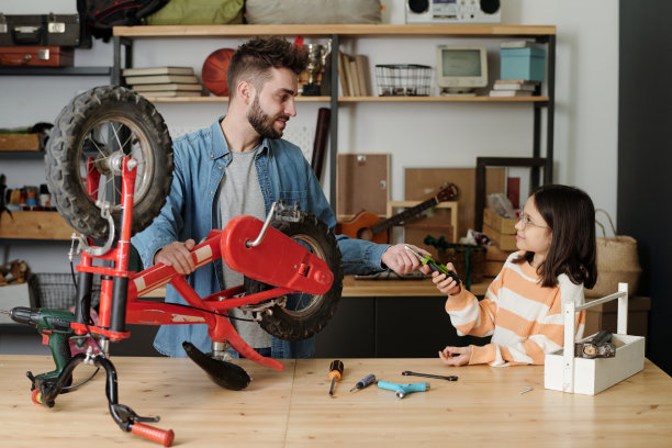 穿着条纹套头衫的小女孩将钳子递给正在修理自行车的父亲图片下载