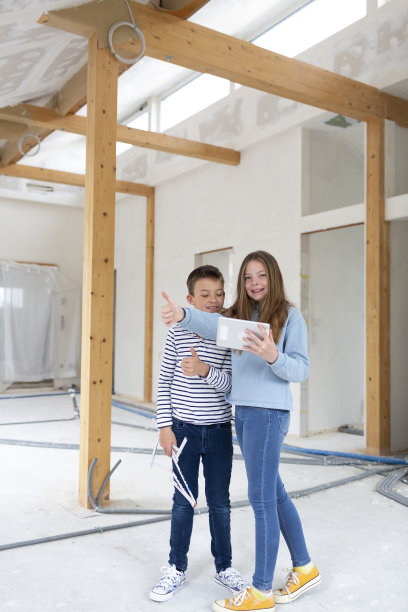 弟弟和妹妹在他们的新房间阁楼公寓的施工现场，用平板电脑，检查进展和享受图片下载