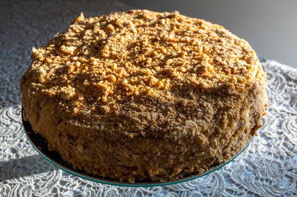 著名的拿破仑蛋糕烤在玻璃托盘上，上面装饰着酥脆的碎面包，阳光从侧面照射进来图片下载
