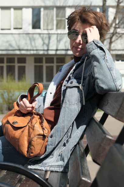 女人坐在阳光明媚的街道上的长凳上图片下载