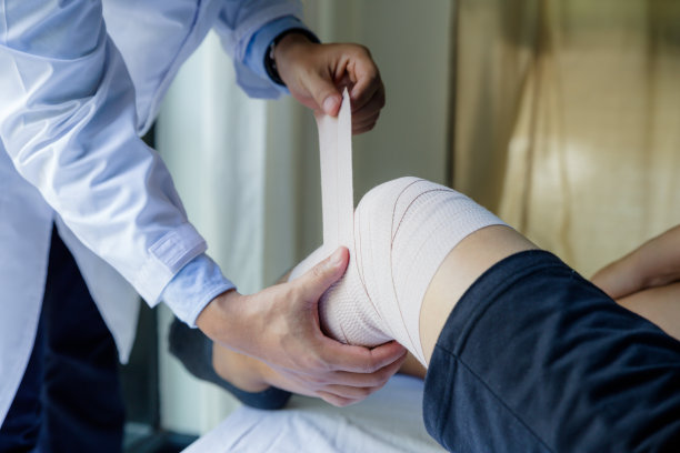 医生为患者膝盖缠绕医用绷带图片下载