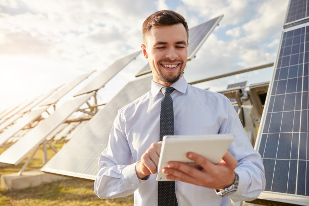 兴高采烈的商人在太阳能农场上使用平板电脑图片下载