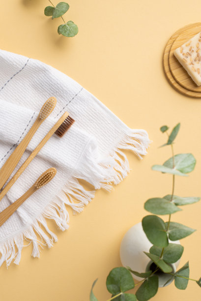 俯视图垂直照片的花瓶与桉树白色棉花毛巾牙刷和肥皂在竹子的立场上孤立的粉彩米色背景图片下载