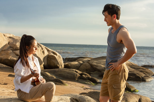 年轻的情侣在海滩的岩石上享受一个美丽的暑假-照片图片下载