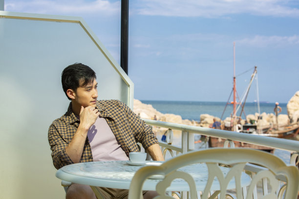 独自旅行的方曼在渔船码头附近的一家餐馆里看风景-照片图片下载