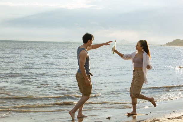 年轻夫妇准备把一只瓶子扔进大海拍照片图片下载