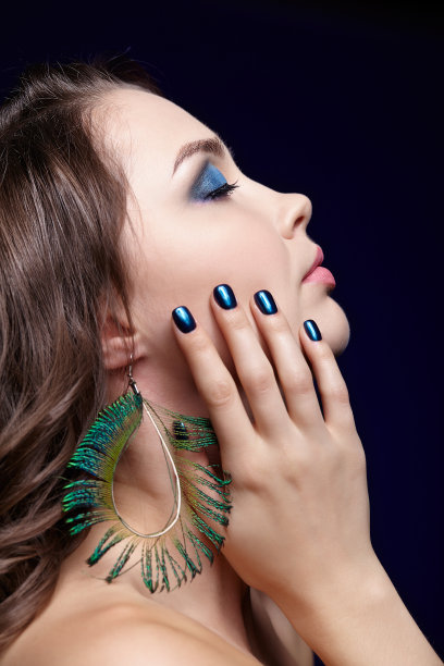 美丽的黑发女人肖像在黑色背景和孔雀羽毛耳环图片下载