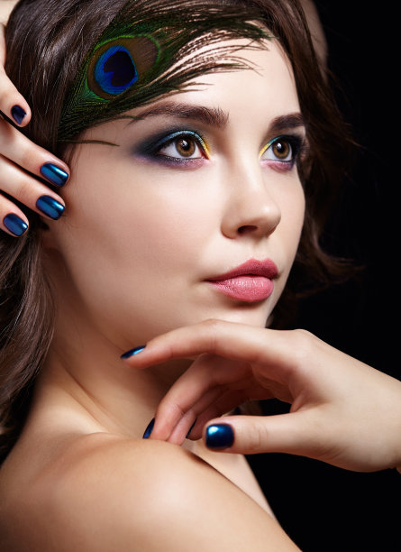 美丽的黑发女人肖像在黑色背景和孔雀羽毛图片下载