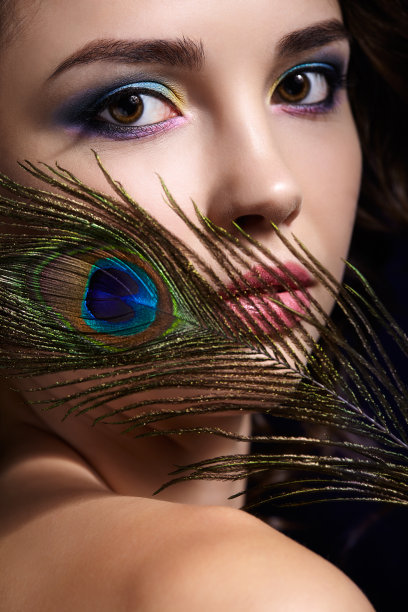 美丽的黑发女人肖像在黑色背景和孔雀羽毛图片下载
