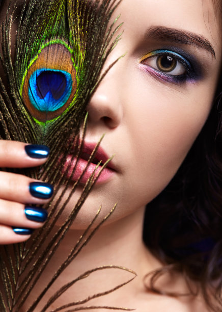 美丽的黑发女人肖像在黑色背景和孔雀羽毛图片下载