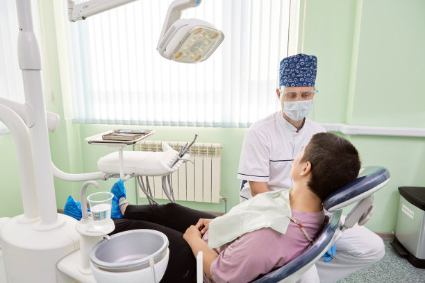 在牙科诊所的女人和牙医。病人坐在牙科扶手椅上。图片下载